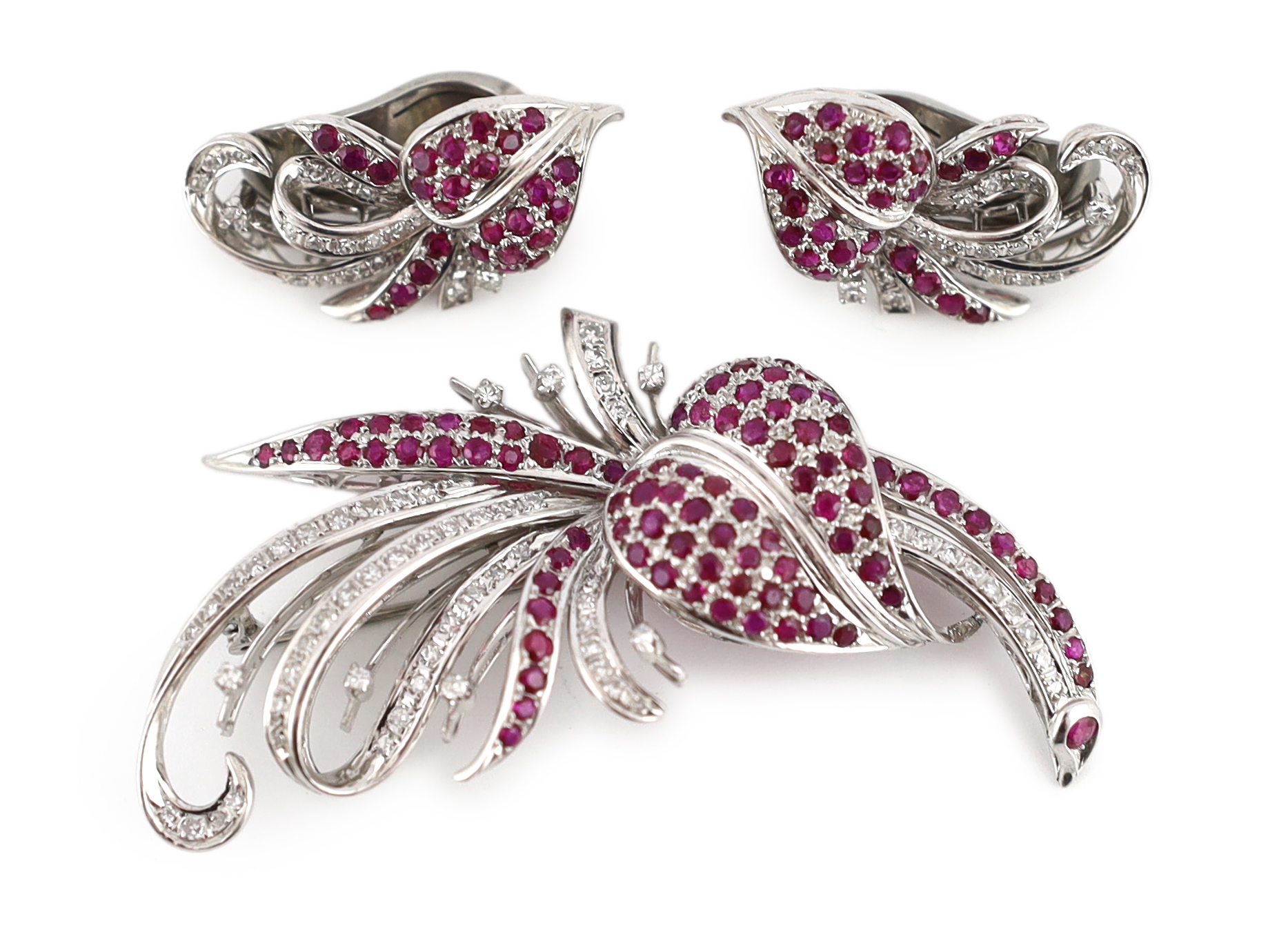 A suite of platinum?, diamond and ruby set cluster jewellery, comprising a spray brooch and pair of matching ear clips